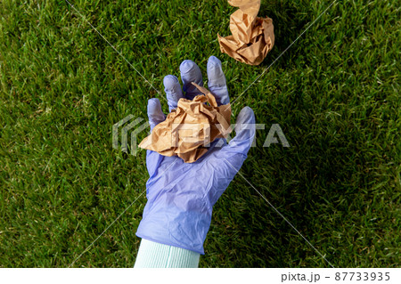 close up of hand in glove picking paper waste close up of hand in glove picking paper waste 87733935