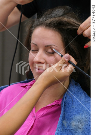 Makeup artist apply makeup on the eyes of young woman. Professional makeup artist applying makeup for bride. 87734043