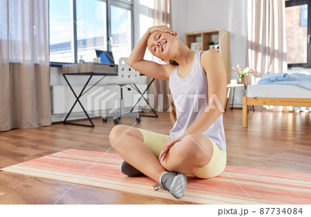 happy teenage girl exercising on yoga mat at home 87734084