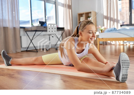happy teenage girl exercising on yoga mat at home happy teenage girl exercising on yoga mat at home 87734089