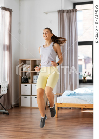 smiling teenage girl running on spot at home 87734095