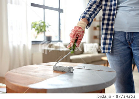 woman painting old wooden table in grey color 87734253