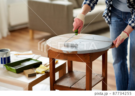 woman painting old wooden table in grey color woman painting old wooden table in grey color 87734255