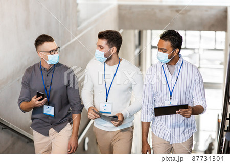 businessmen in masks with name tags going upstairs businessmen in masks with name tags going upstairs 87734304