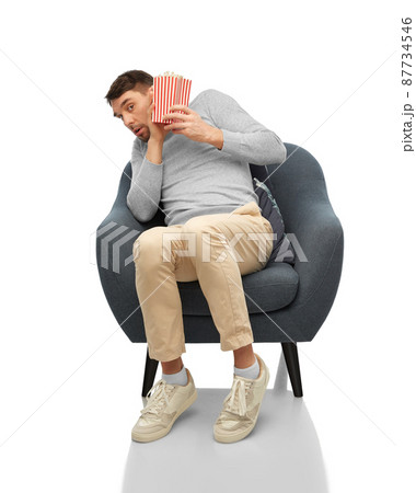 scared man with popcorn sitting in chair scared man with popcorn sitting in chair 87734546