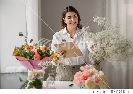 happy woman with clipboard and flowers at studio 87734817