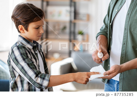 father treats son's injured finger with antiseptic 87735285