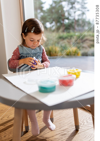 baby girl with modeling clay playing at home 87735308