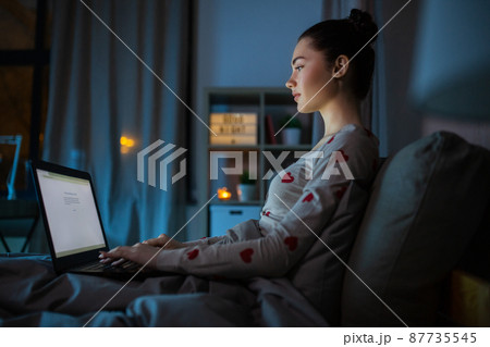 teenage girl with laptop in bed at home at night teenage girl with laptop in bed at home at night 87735545