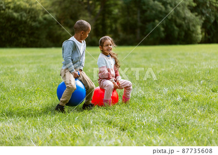 happy children bouncing on hopper balls at park happy children bouncing on hopper balls at park 87735608