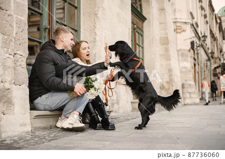 Lovely couple petting their dog in the street of old town Lovely couple petting their dog in the street of old town 87736060
