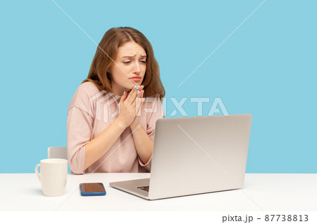 Please, begging for help. Young woman employee holding hands in praying gesture and talking on video call on laptop, asking heartily, pleading with desperate face. indoor studio shot, blue background Please, begging for help. Young woman employee holding hands in praying gesture and talking on video call on laptop, asking heartily, pleading with desperate face. indoor studio shot, blue background 87738813