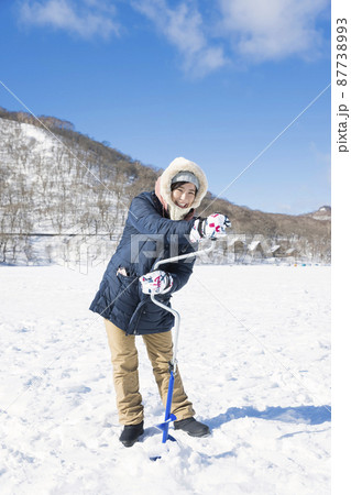湖の氷にドリルで穴をあける女性　ワカサギ釣りイメージ 87738993