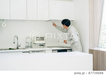 キッチンと作業着姿の男性（換気扇） 87739088