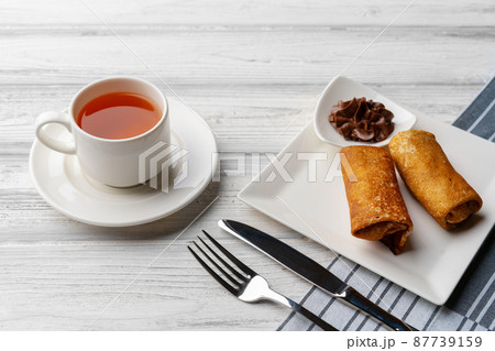 Russian pancakes with filling lying on a plate on table Russian pancakes with filling lying on a plate on table 87739159