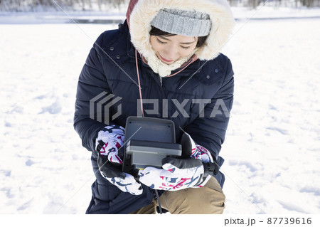 氷上わかさぎ釣りイメージ　魚群探知機を見る若い女性 87739616