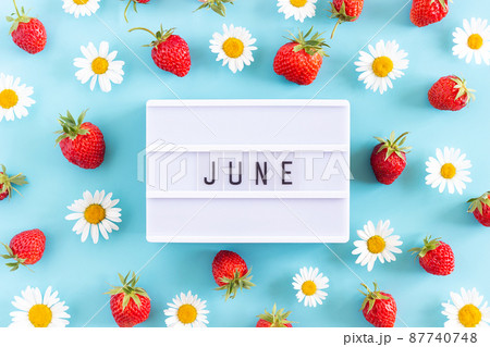 Summer month June text on light box and strawberry, chamomile flowers on blue background. Top view Flat lay. Creative concept Hello June. Top view, Flat lay, greeting card 87740748