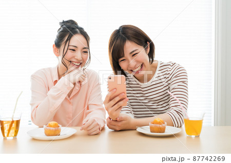 二人でスマホを見る女性 87742269