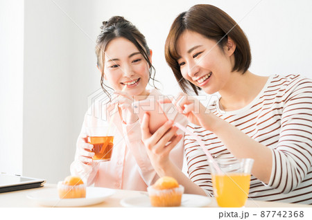 二人でスマホを見る女性 87742368
