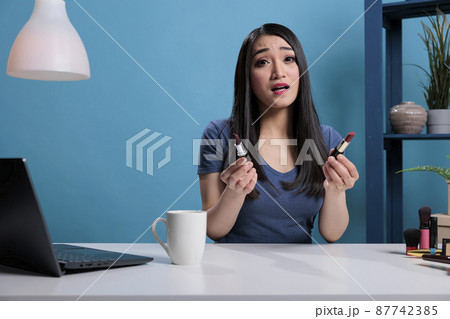 Asian social media influencer holding lipstick talking with remote subscribes Asian social media influencer holding lipstick talking with remote subscribes 87742385