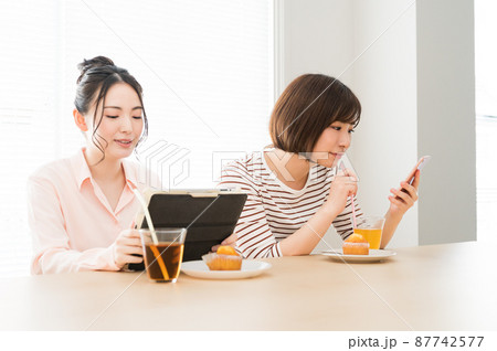 お茶しながら端末を見る二人の女性 お茶しながら端末を見る二人の女性 87742577