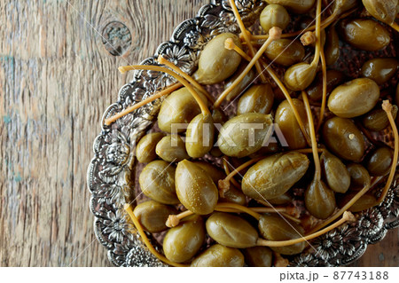 Pickled caper berries in metal dish . Pickled caper berries in metal dish . 87743188
