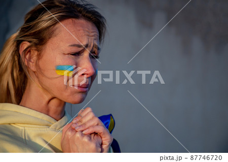 War portrait of Ukrainian woman with national flag on cheek crying War portrait of Ukrainian woman with national flag on cheek crying 87746720