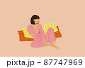 Young brunette woman in blue pyjama sitting relaxed on beige background 87747969