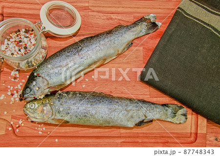 Fresh raw rainbow trouts with spices on wooden board. Healthy food and dieting concept. Close-up 87748343