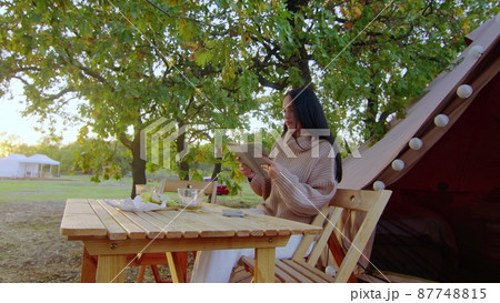 Mom and daughter sit at a wooden table in nature and take a selfie on the phone. Family on a picnic. 87748815