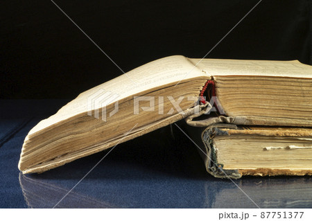 Aging book rests upon glass table with reflection Aging book rests upon glass table with reflection 87751377