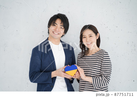 ウクライナ国旗配色のハートを救う笑顔の男女 87751711