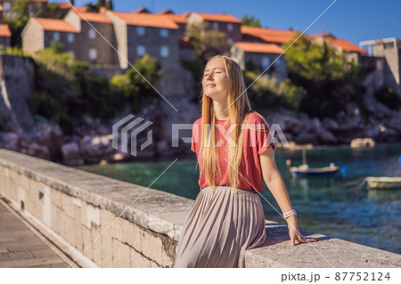Woman tourist on background of beautiful view of the island of St. Stephen, Sveti Stefan on the Budva Riviera, Budva, Montenegro. Travel to Montenegro concept 87752124