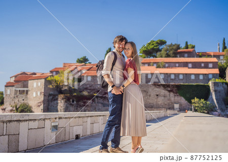 Man and woman tourists on background of beautiful view of the island of St. Stephen, Sveti Stefan on the Budva Riviera, Budva, Montenegro. Travel to Montenegro concept 87752125