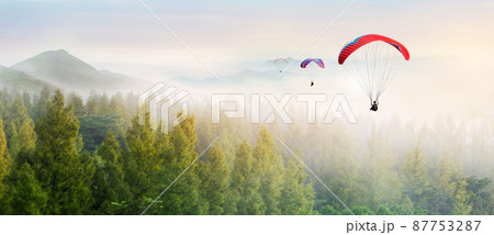 Paragliding in the sky. Paraglider  flying over Landscape sun set Concept of extreme sport, taking adventure challenge. 87753287