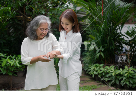 An old elderly Asian woman and walking in the backyard with her daughter.  Concept of happy retirement With care from a caregiver and Savings and senior health insurance, Happy family 87753951