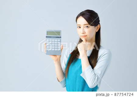 計算機を持ったエプロン姿の若い主婦 計算機を持ったエプロン姿の若い主婦 87754724