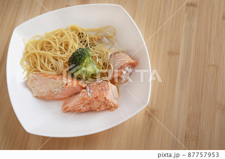 Spaghetti with salmon and broccoli in square plate on bamboo table. Healthy food Spaghetti with salmon and broccoli in square plate on bamboo table. Healthy food 87757953