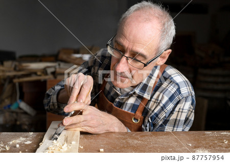 Close up of a Carpenter carving wood with chisel Close up of a Carpenter carving wood with chisel 87757954