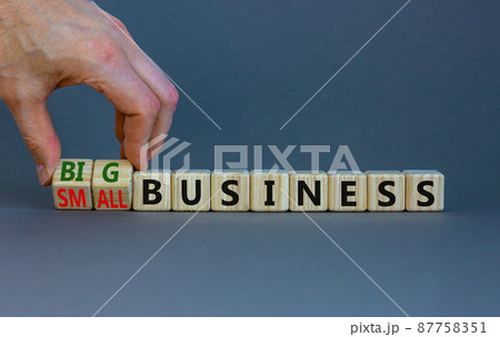 Big or small business symbol. Businessman turns wooden cubes, changes words small business to big business. Beautiful grey background, copy space. Big or small business concept. 87758351
