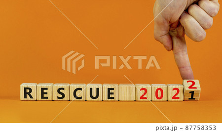 2022 rescue new year symbol. Businessman turns wooden cubes and changes words 'rescue 2021' to 'rescue 2022'. Beautiful orange background, copy space. Business, 2022 rescue new year concept. 87758353