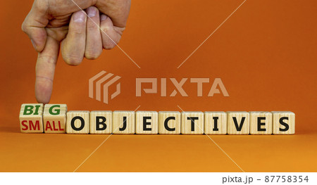 Big or small objectives symbol. Businessman turns wooden cubes, changes words small objectives to big objectives. Beautiful orange background, copy space. Business, big or small objectives concept. 87758354