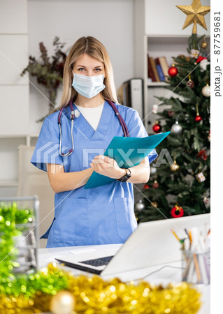 Doctor in mask working in office at Christmas 87759681