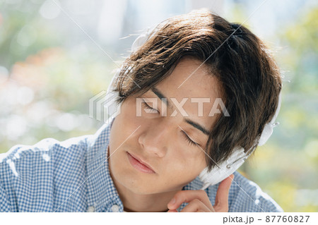 音楽を聞く若い男性 87760827