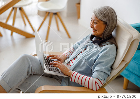 Cheerful woman using modern laptop at home 87761800