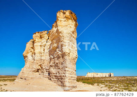 Large white rock pillars sticking out of flat desert and bold blue sky 87762429