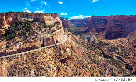 Road driving through large desert canyon cliffs and valley Road driving through large desert canyon cliffs and valley 87762567