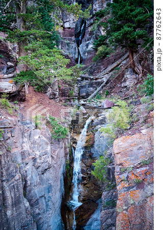Tiers of very tall waterfalls cutting through canyon gorge in the mountains 87762643