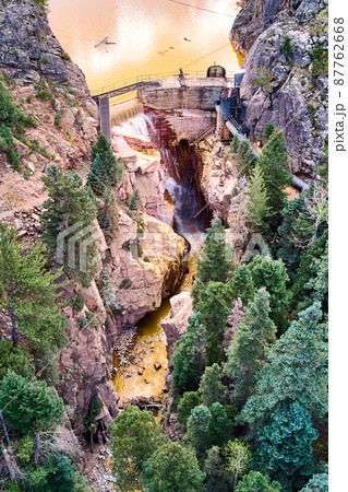 Vertical aerial view of large dam leading to gorge canyon with waterfall Vertical aerial view of large dam leading to gorge canyon with waterfall 87762668