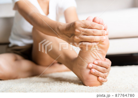 Asian woman feeling pain in her foot at home 87764780